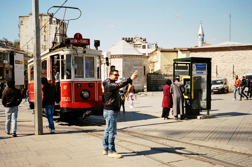 Historic tram passing through Taksim Square and İstiklal Avenue. It was common to see young boys jump onto the tram and hang on to the bars outside the tram for a free ride.